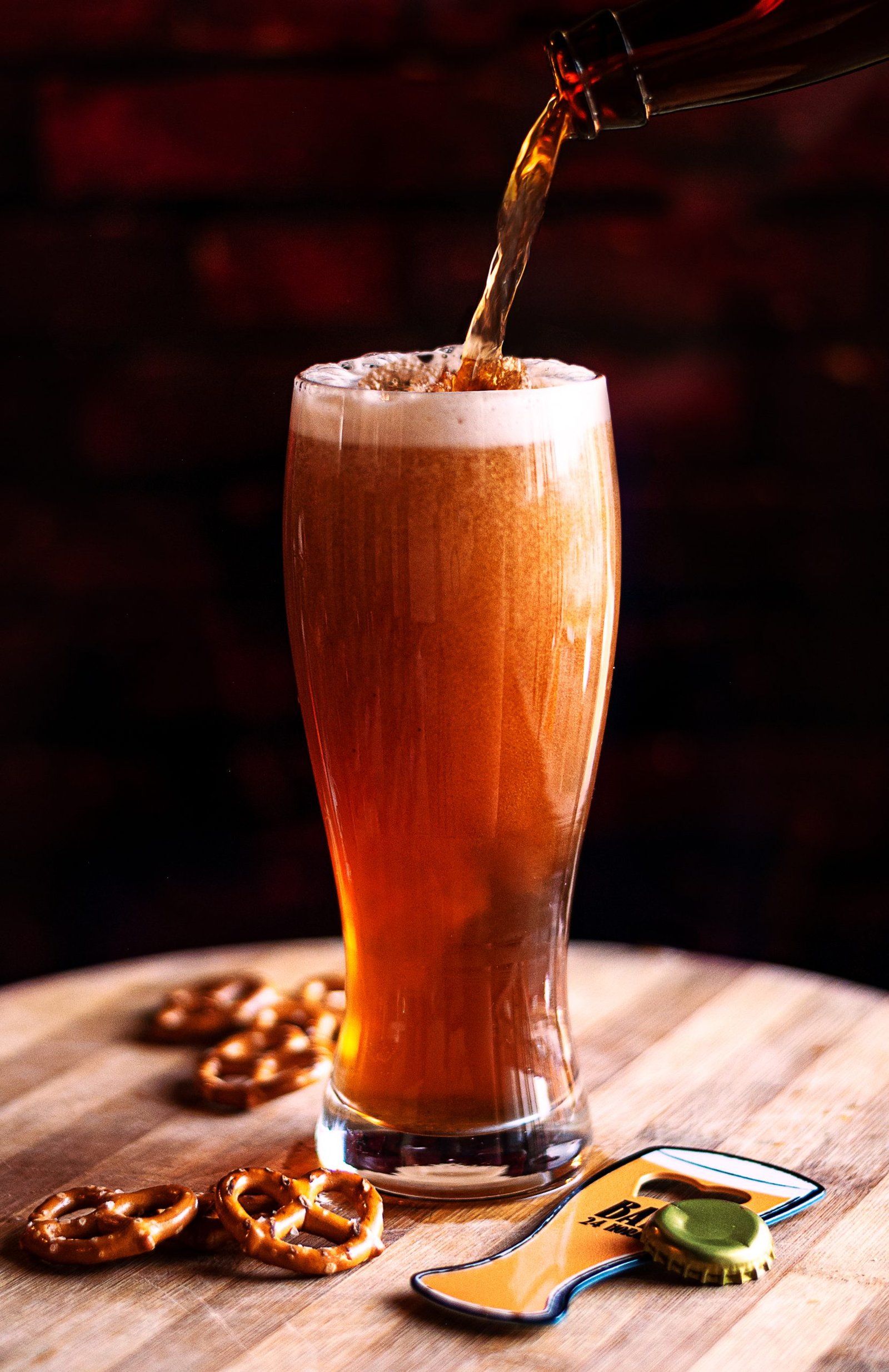The process of pouring amber beer into the glass on a wooden board and snacks